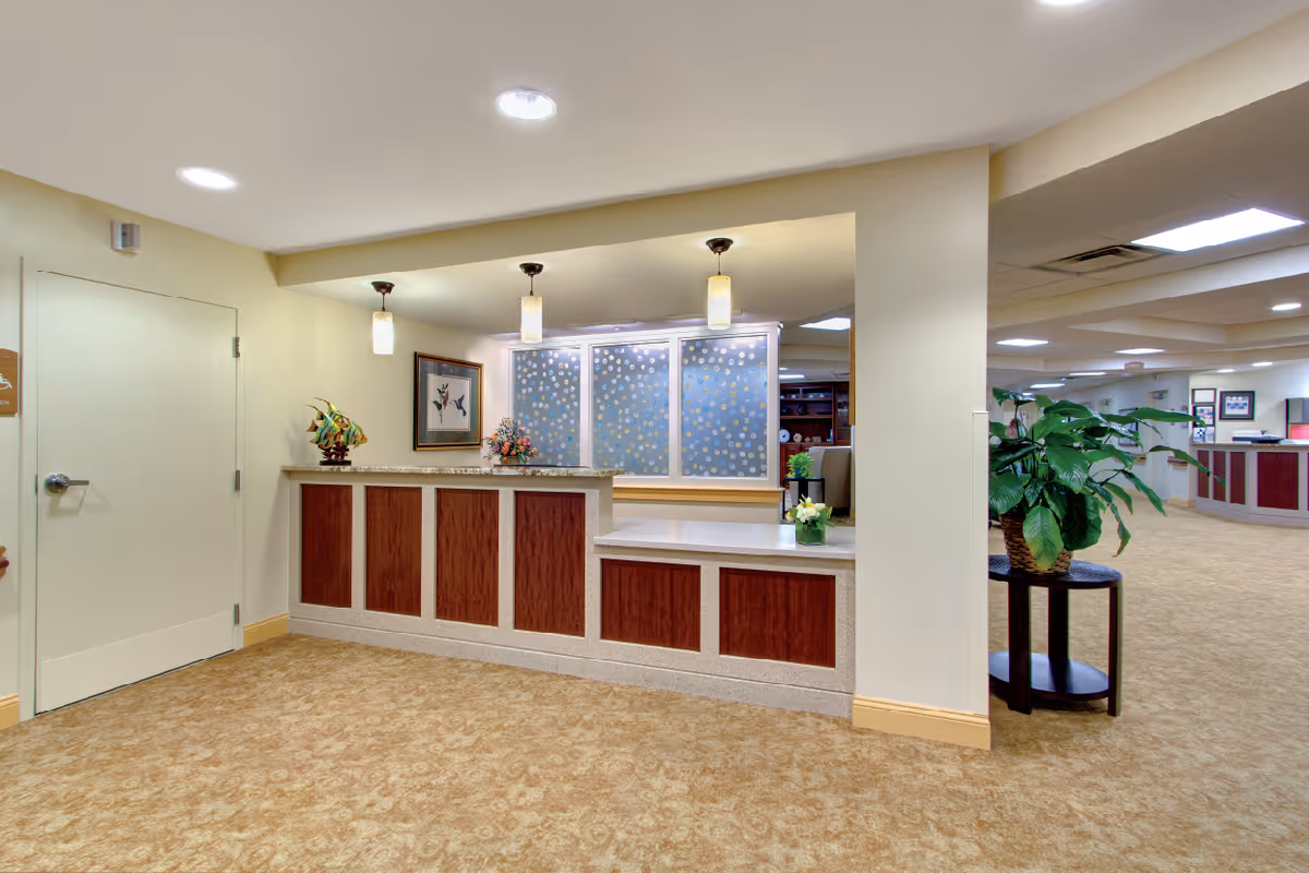 Reception desk and lobby area with pendant lights, decorative panels, and potted plants.