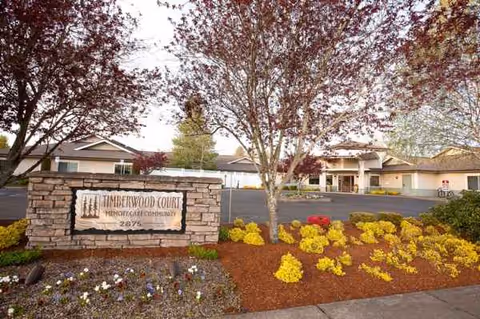 Timberwood Court Memory Care sign with landscaped front yard and building in background.