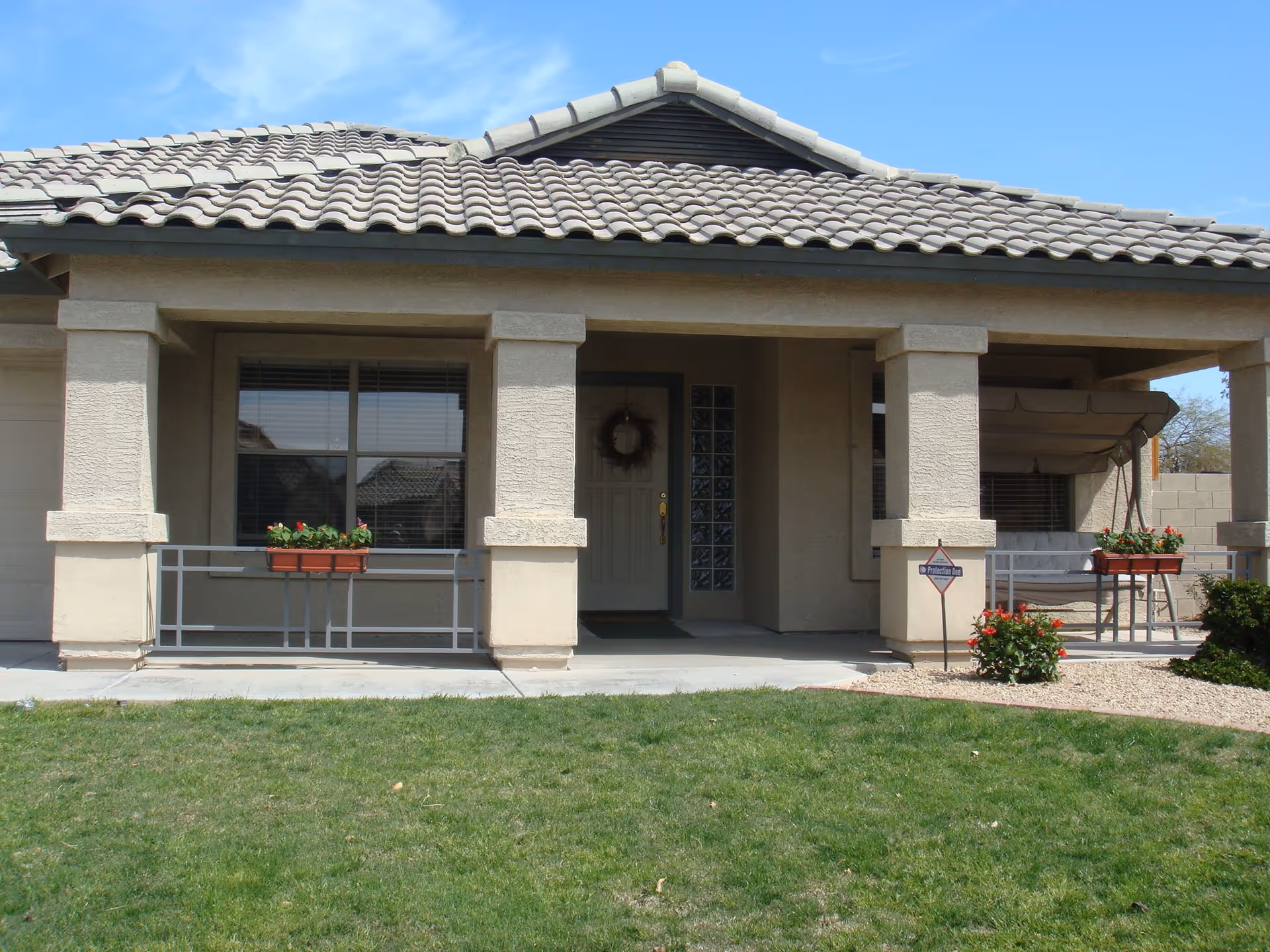 A front view of a single-story house with a tiled roof, potted plants, and a porch.