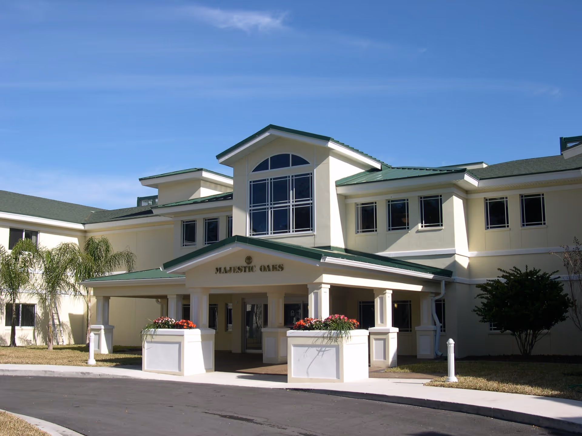 Exterior view of Majestic Oaks senior living facility with entrance, columns, and planters.