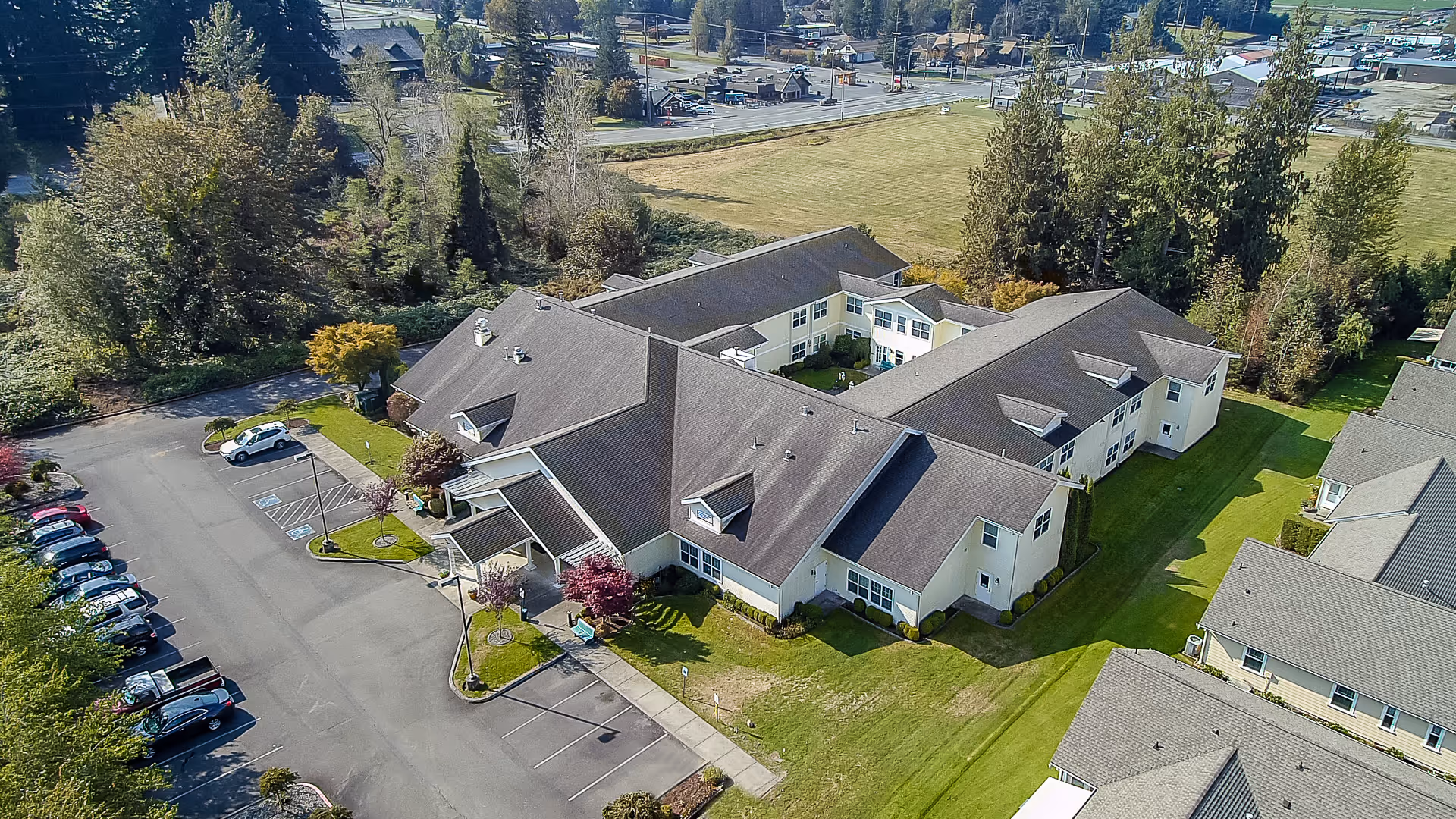 Aerial view of the Cascade Place Assisted Living and Memory Care building with a parking lot, landscaped lawns and surrounding trees.