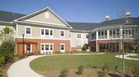 Exterior view of Arbor Terrace Crabapple facility with curved walkway and lawn.