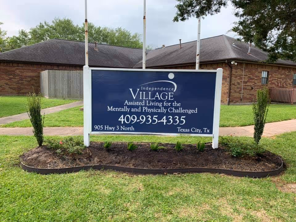 Blue Independence Village assisted living sign on a lawn in front of a brick building