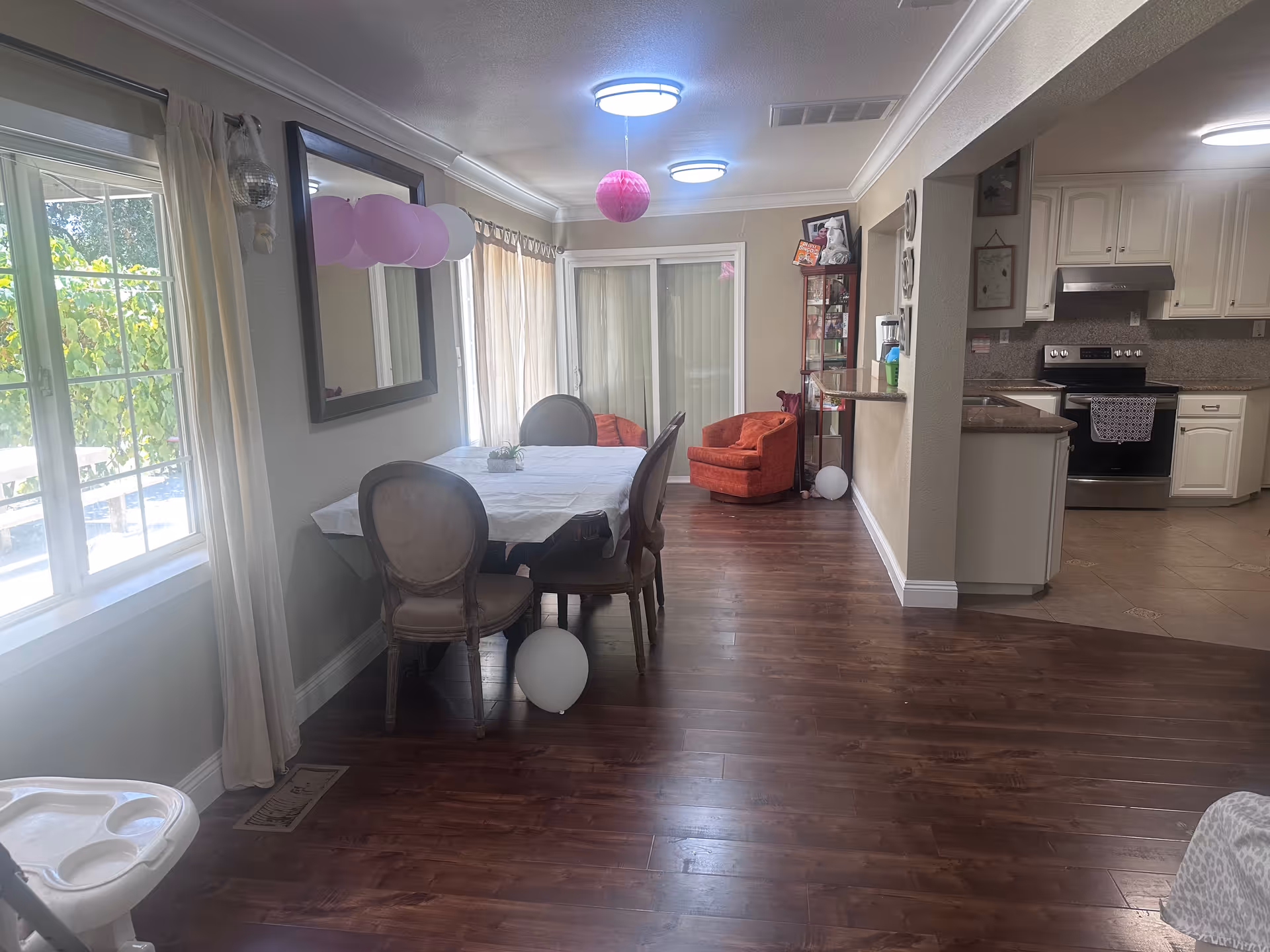 Open dining area with a table and chairs, balloons, and an adjacent kitchen.