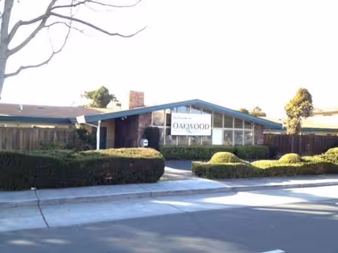 Front view of Oakwood Memory & Senior Care, with sign, hedges, and a driveway.