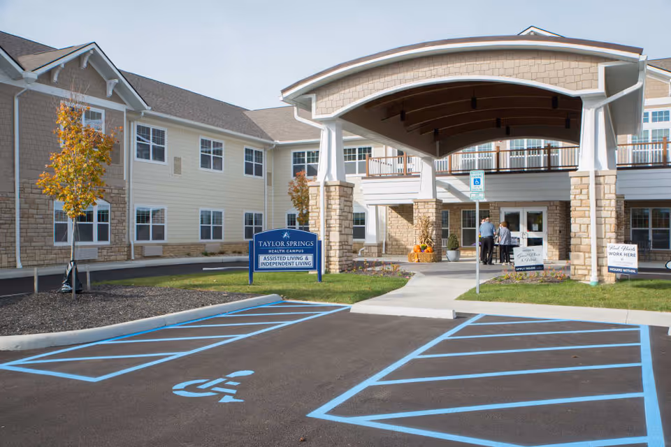 Front entrance of Taylor Springs Health Campus with a covered porte-cochere, handicap parking spaces, and a sign for assisted and independent living.