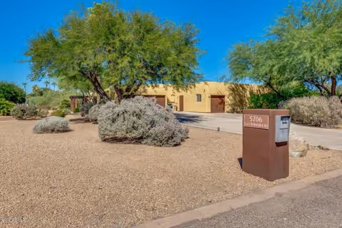 Desert landscaping surrounds a single-story beige assisted-living building with driveway and mailbox.