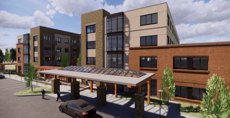 Front entrance of a multi-story senior living building with a covered porte-cochère, parked car, and landscaped grounds.