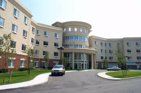 Exterior view of Fulton Commons Care Center with curved glass entrance and driveways.