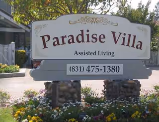 Paradise Villa Assisted Living sign in front yard with colorful flowers.