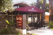 Front entrance of Sierra Valley Rehab Center with a maroon awning over a gated walkway and a freestanding sign by the sidewalk.