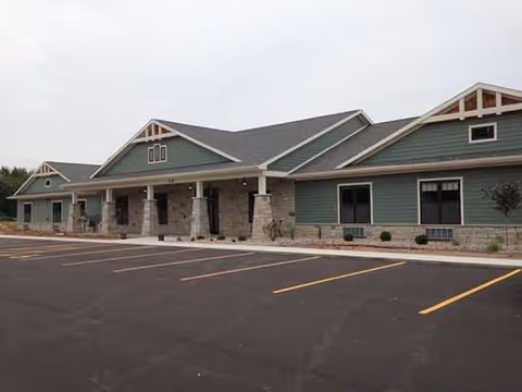 Front exterior view of Country Villa Assisted Living facility with parking and entry columns.