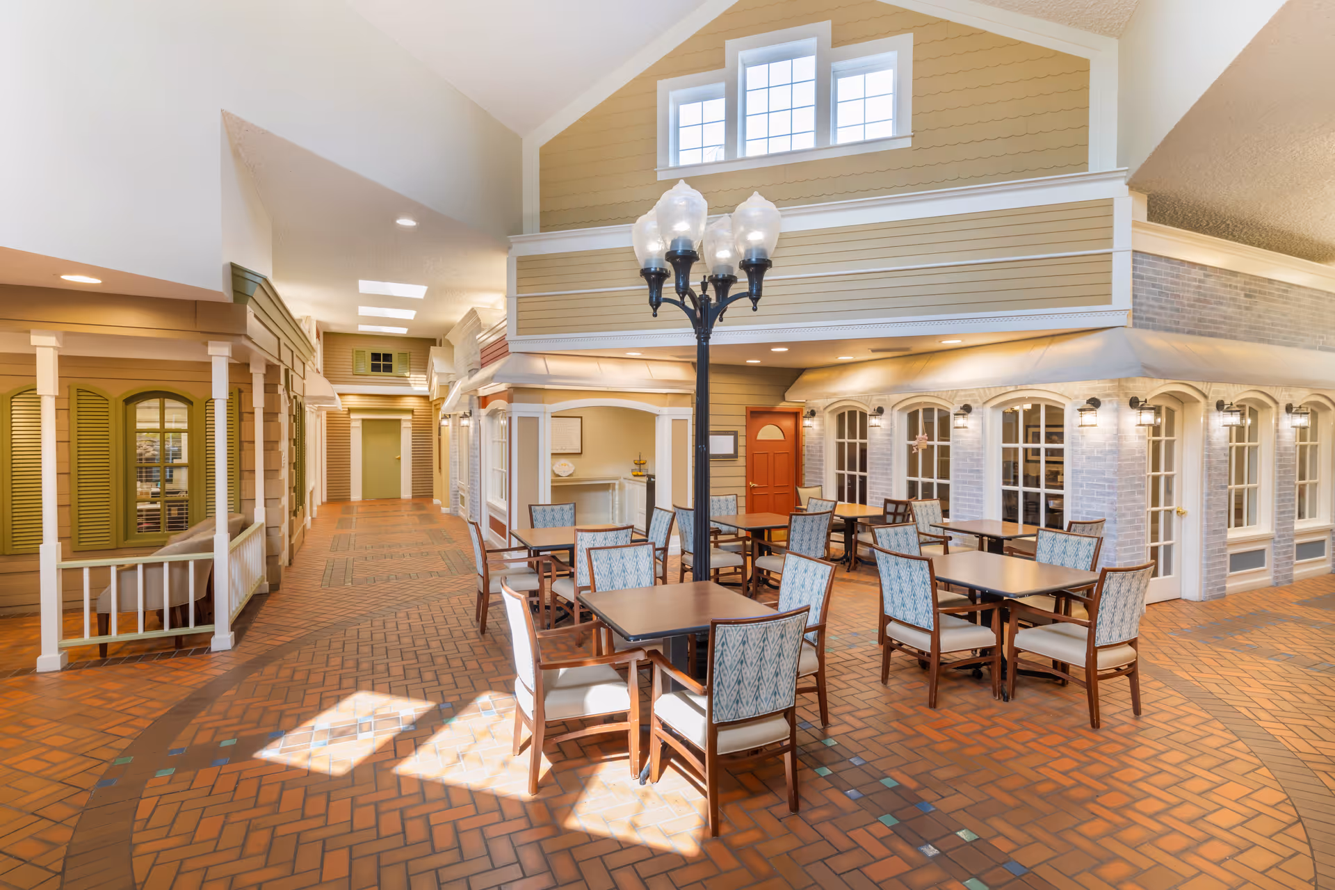 Indoor dining area styled like a small-town streetscape with tables and chairs, a central lamppost, and storefront-like façades.