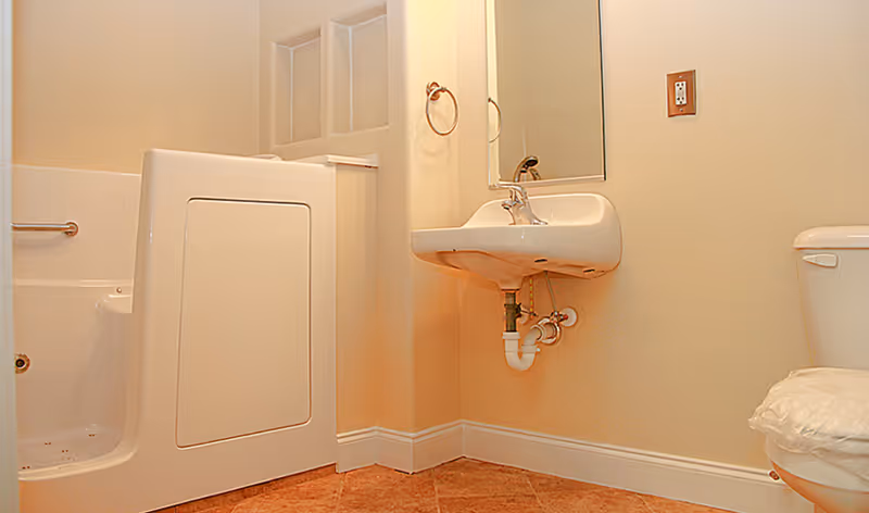 Small bathroom interior with a walk-in tub, wall-mounted sink and a toilet.