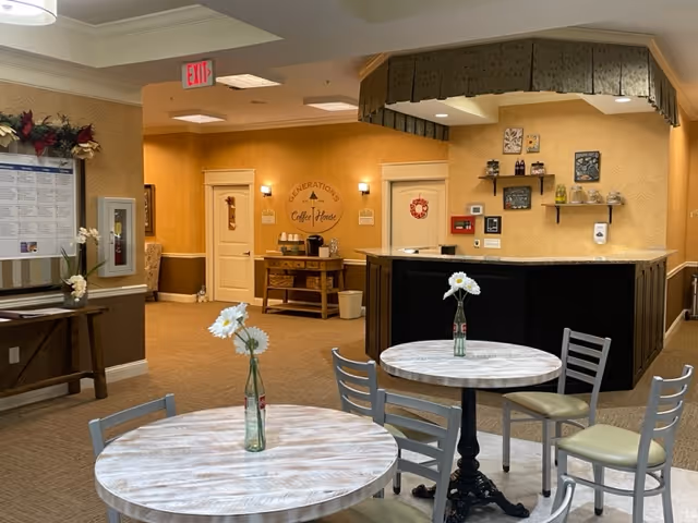 Small communal dining and coffee area with round tables and chairs facing a counter and coffee station.