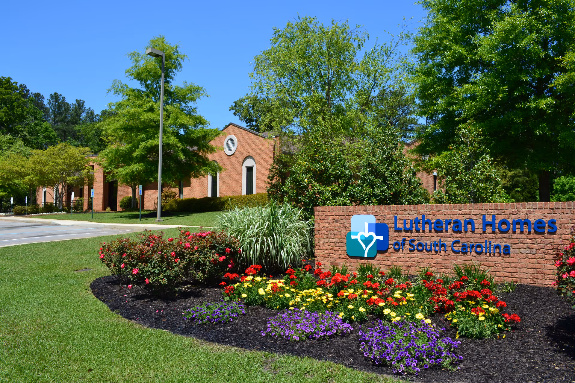Brick building and landscaped flowerbed with a 'Lutheran Homes of South Carolina' sign in front.