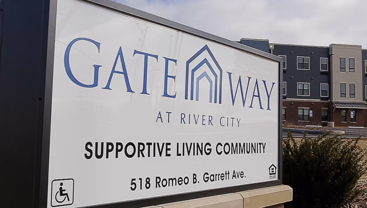 Outdoor sign for GateWay at River City Supportive Living Community located at 518 Romeo B. Garrett Ave, with a multi-story building and parking lot visible in the background.