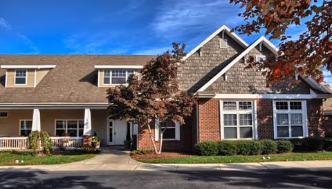 Exterior view of a senior living facility with brick facade and gabled roof.