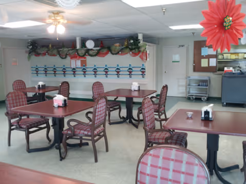 Indoor dining room with red plaid chairs and holiday decorations around tables.