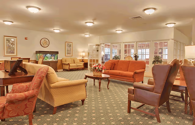 Spacious senior living lounge with sofas, armchairs, coffee table, and an aquarium.