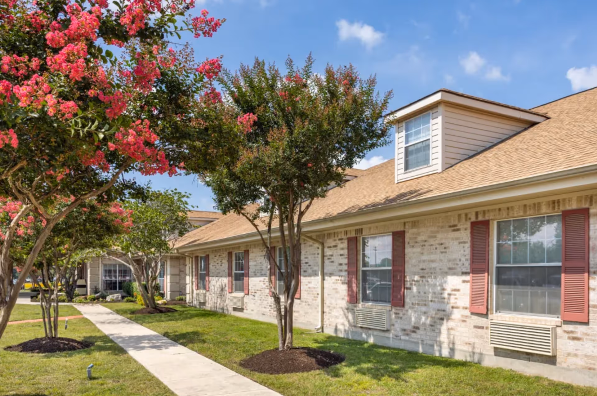 Exterior view of Mystic Park Nursing and Rehabilitation Center with trees along a walkway.