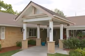 Entrance to Arvada Care and Rehabilitation Center with a covered portico and brick columns.