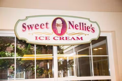 Exterior wall with a Sweet Nellie's Ice Cream sign above a window.