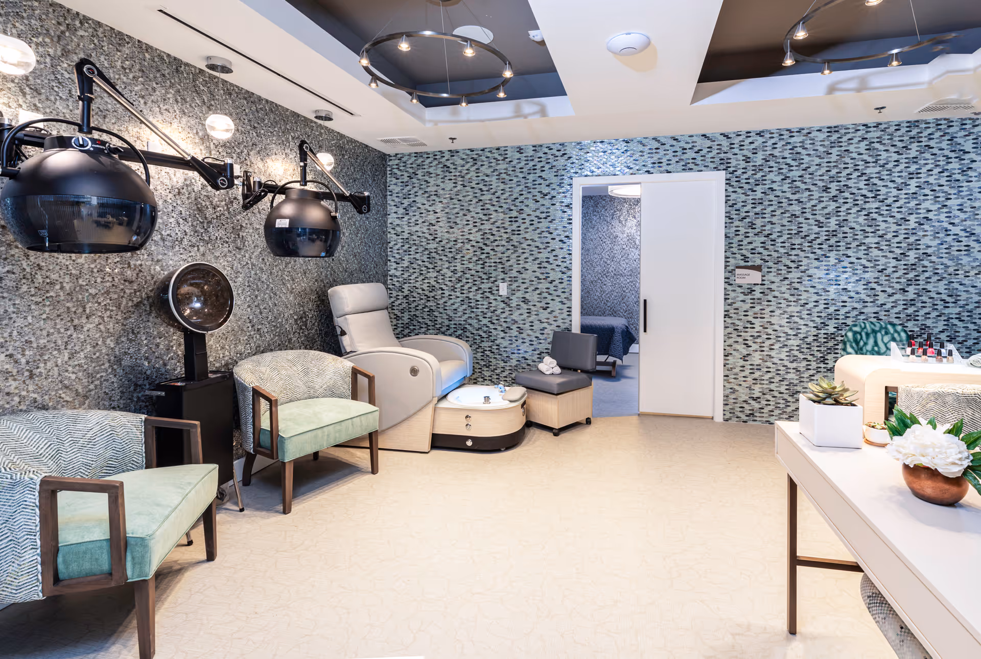 Salon area with hair drying chairs, pedicure stations, and mosaic walls in a senior living facility.
