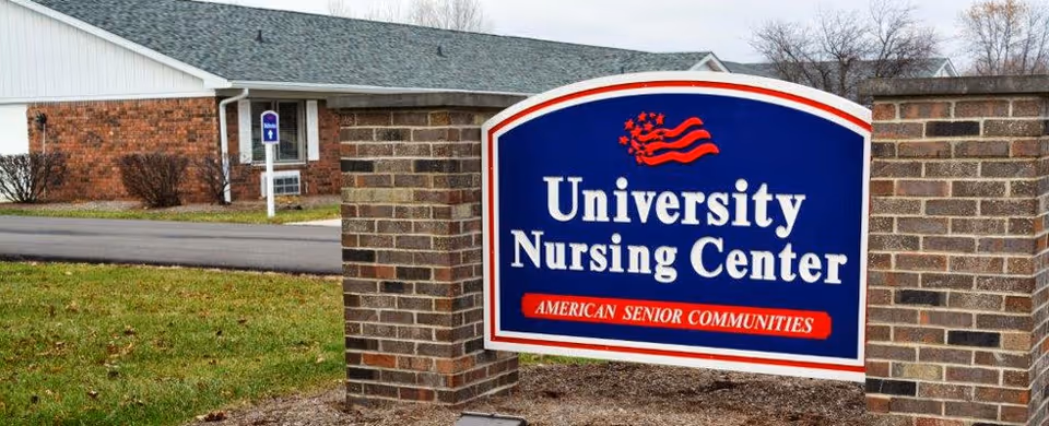 A large blue sign reading "University Nursing Center" mounted between brick pillars in front of the facility.