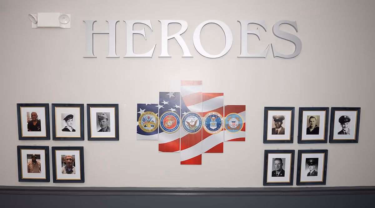 Wall display reading "HEROES" with a central American flag and military seals flanked by framed veteran portraits.