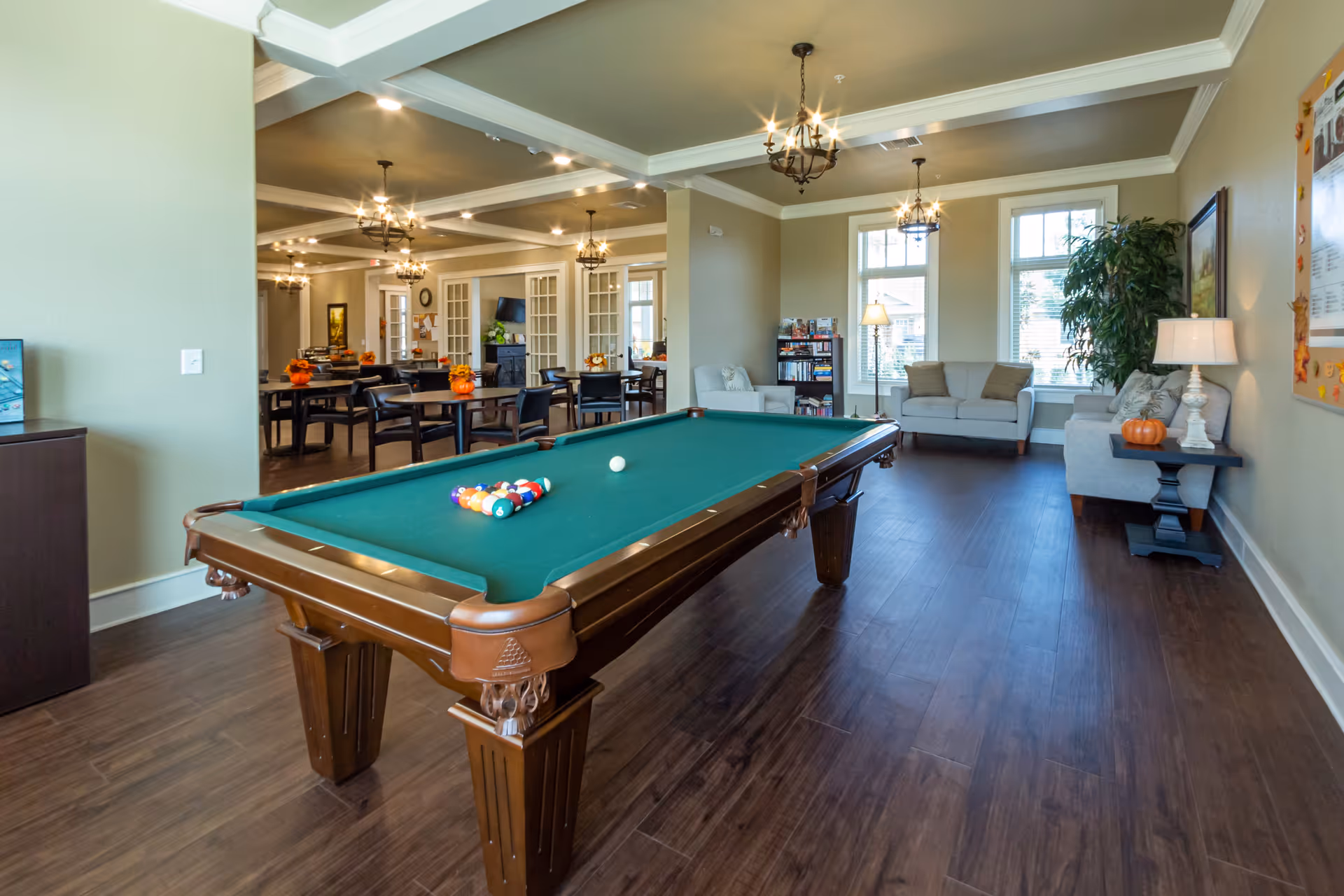 Bright communal lounge with a pool table in the foreground and dining and seating areas in the background.