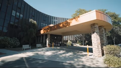 Exterior view of a curved entrance canopy and stone columns at a senior living facility.