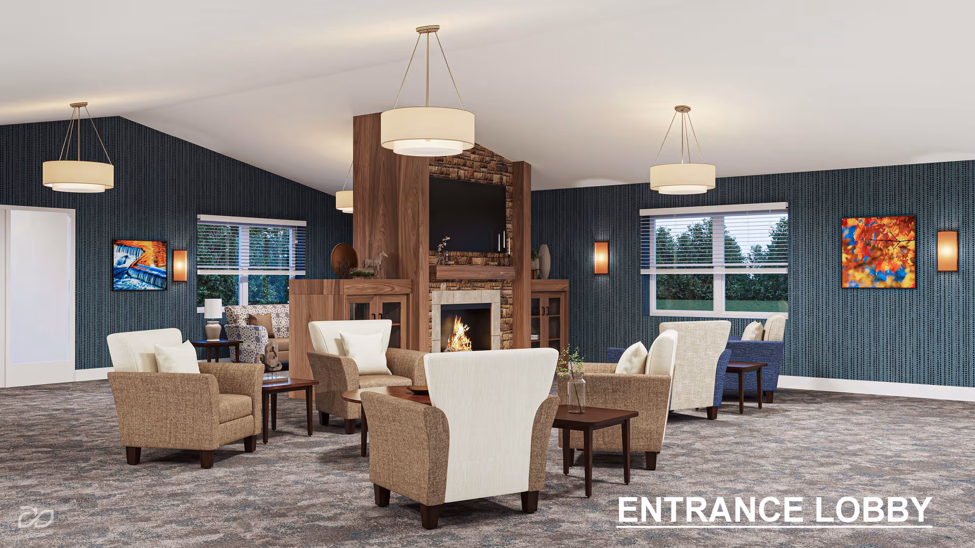 A spacious and well-lit entrance lobby with multiple comfortable armchairs arranged around small wooden tables. The room features a central fireplace with a mounted TV above it, wood-paneled accents, patterned carpet, blue textured walls, and large windows with white blinds. Modern pendant lights hang from the ceiling, and colorful artwork decorates the walls.