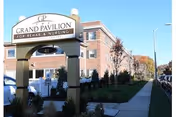 Brick building with an arched entrance sign reading Grand Pavilion for Rehab and Nursing.