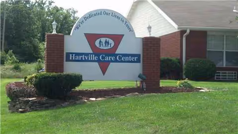 Exterior view of Hartville Care Center sign with brick pillars and green lawn.