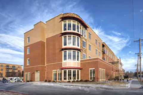 Front exterior of a brick senior living building with large bay windows.