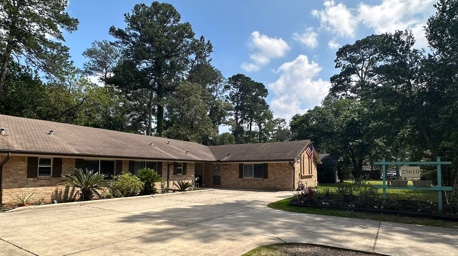 Single-story brick senior living facility exterior with driveway and landscaped front yard.