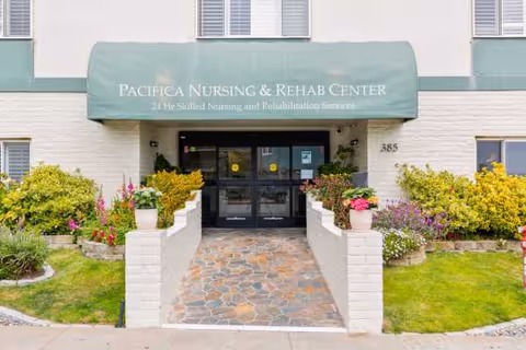 Front entrance of Pacifica Nursing & Rehab Center with green awning and landscaped walkway.