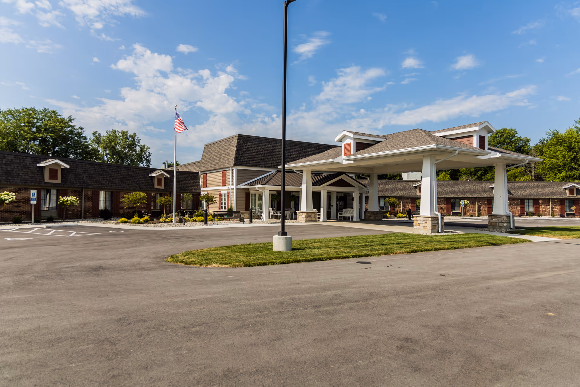 Front exterior of Bowling Green Manor showing a covered entrance, circular driveway, and an American flag.