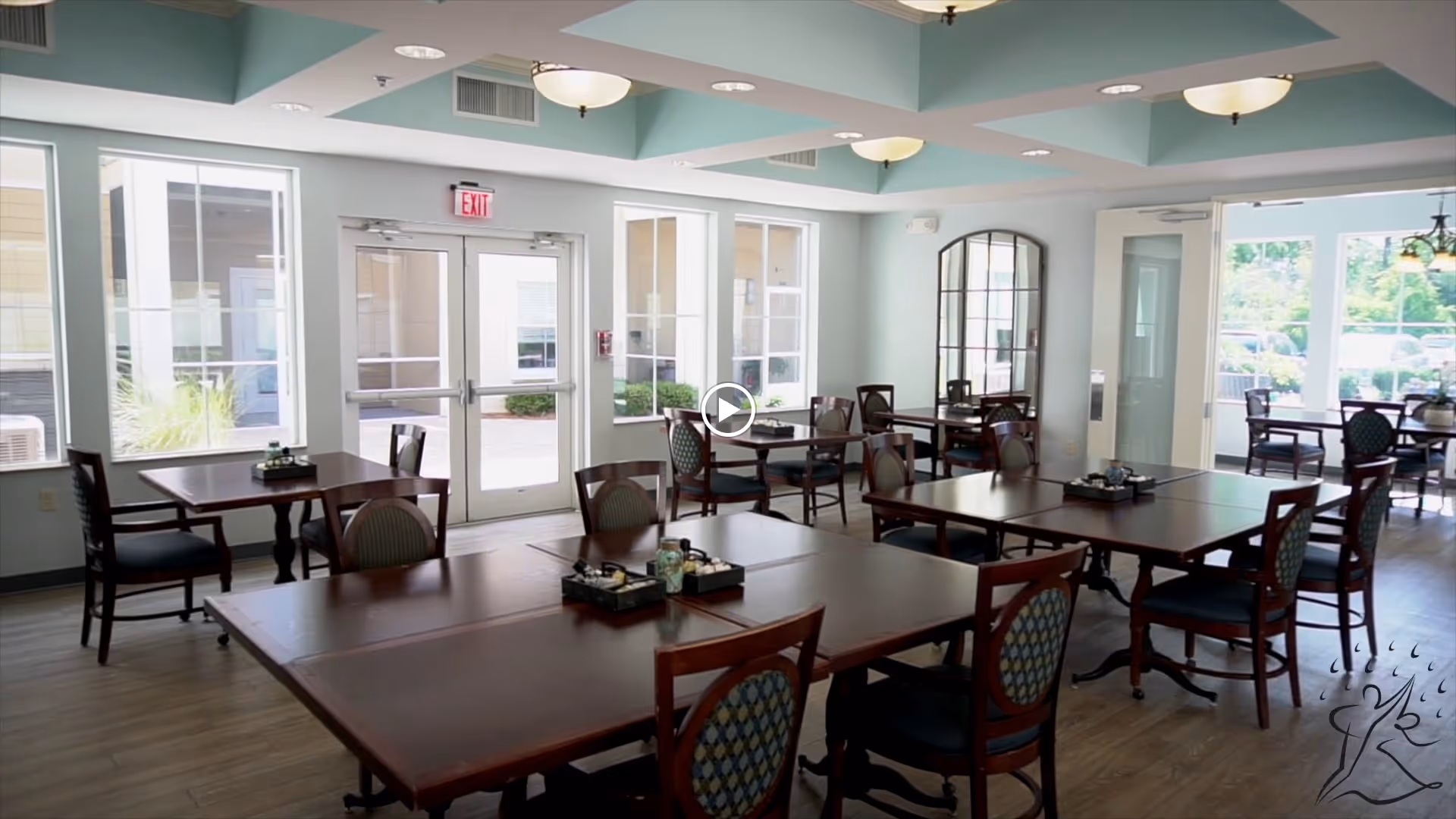 Bright dining room with multiple wooden tables and chairs, large windows and glass doors.