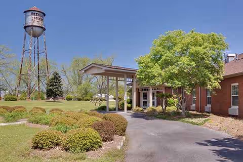 Sunny exterior view of The Oaks - Bethany Assisted Living with entrance and landscaped grounds.