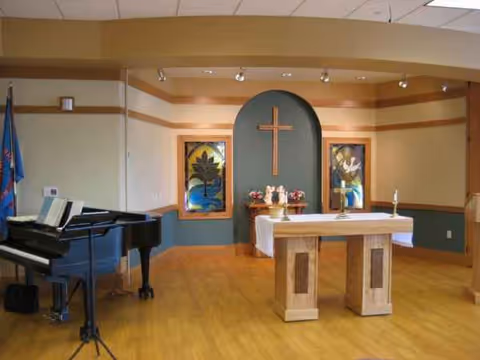 A chapel area inside Parkview Health Center with an altar, cross, paintings, and a piano.