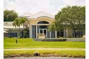 Sunlit exterior view of Sandhill Cove Retirement Living building with lawn and trees.