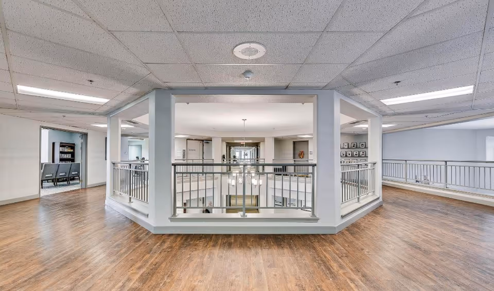 Open interior mezzanine with wood floors and metal railings overlooking a central atrium and adjacent seating areas.