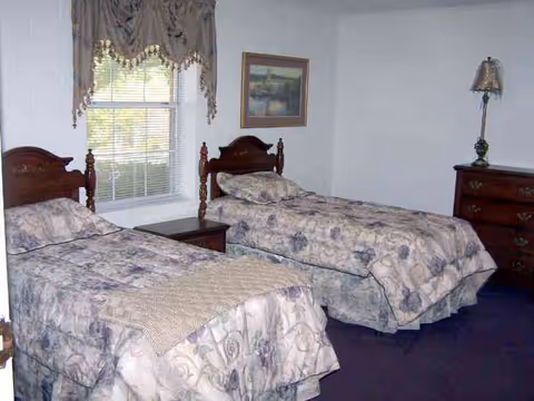 Two single beds with matching bedding and a dresser in a bedroom.