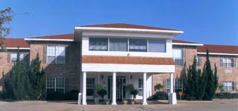 Front exterior of Brandon Court Nursing building with entrance columns and potted plants.