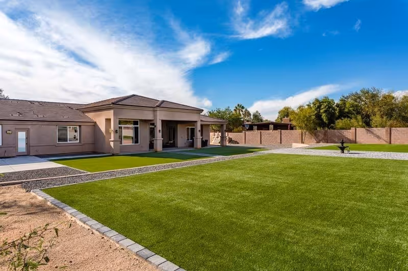 Single-story building with a covered patio facing a large manicured lawn under a blue sky.