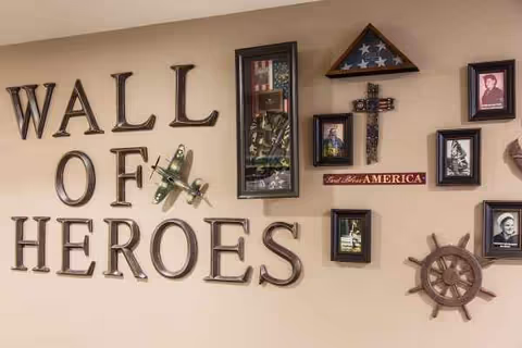 Interior wall features a Wall of Heroes display with framed veteran photos and nautical decor.