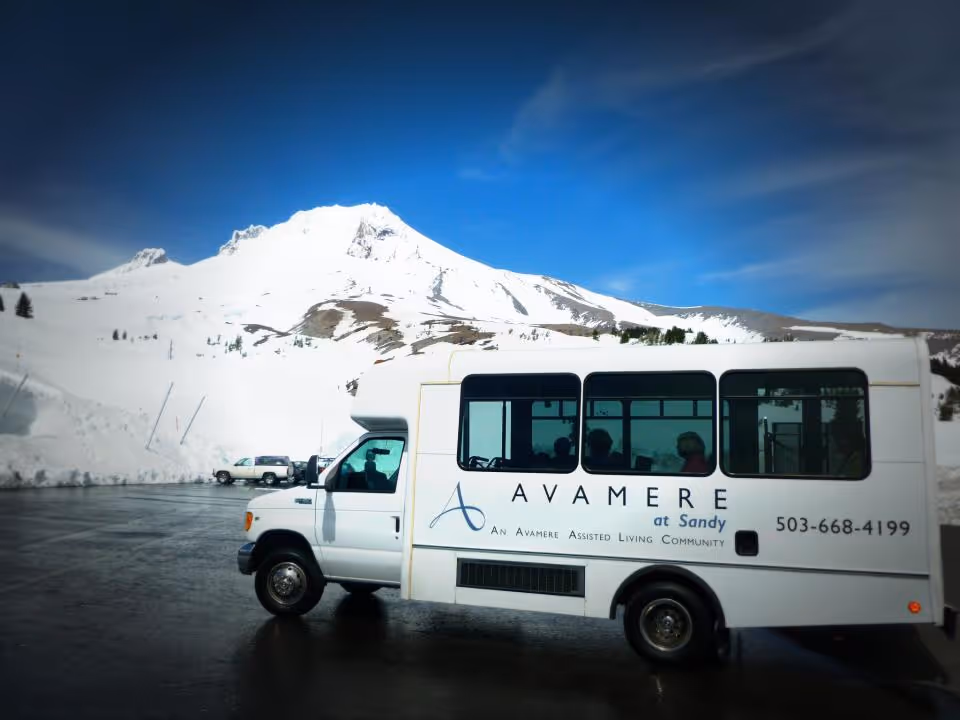 A shuttle bus for Avamere at Sandy parked with a snowy mountain backdrop.