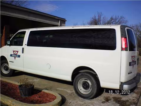 A white Gerald Nursing and Rehab van parked outside a facility with a small landscaped island.